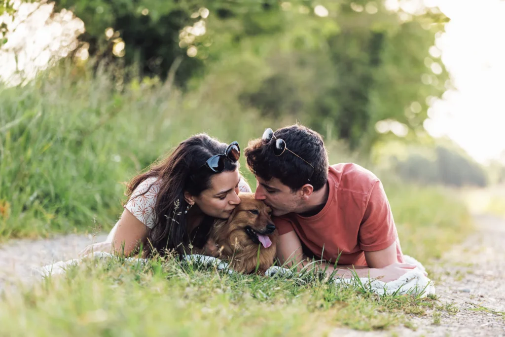 Un couple fait un bisou sur la tête de leur chien